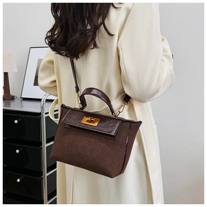 Detail of vintage brown leather handbag with gold twist lock and crossbody strap style