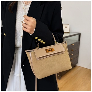 Close-up of a beige faux suede handbag with leather flap and gold-tone turn-lock buckle