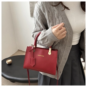 Detailed shot of a red leather crossbody bag with gold hardware and embossed text