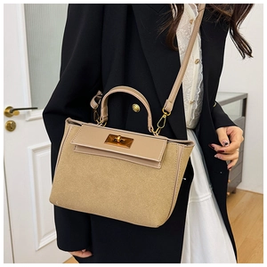 Detailed close-up of khaki leather and suede patchwork bag with golden twist lock clasp