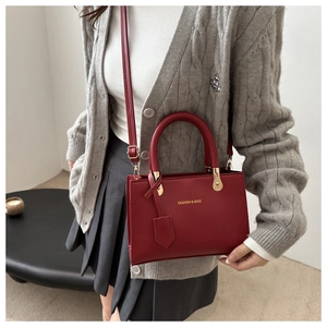 Detail of dark red leather tote bag with gold lettering and adjustable shoulder strap