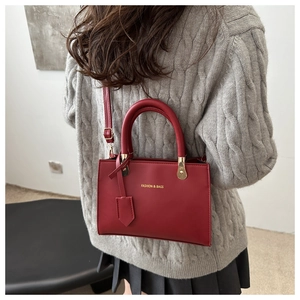 Detail of dark red vintage handbag showing the fashion text and golden metal buckles