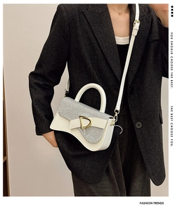 Détail du rabat à paillettes argentées et boucle D sur sac en cuir blanc