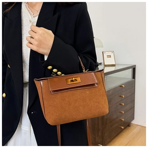 Detailed close-up of brown suede and leather splicing handbag with a gold twist-lock