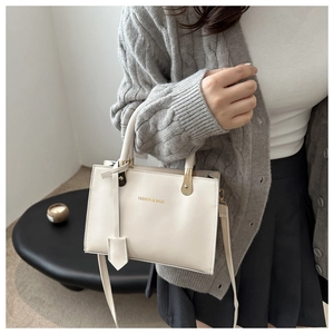 Detail of cream white PU leather handbag with gold hardware and embossed fashion logo