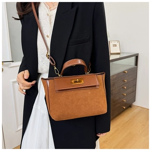Detail of vintage brown suede satchel featuring gold twist-lock and top handle