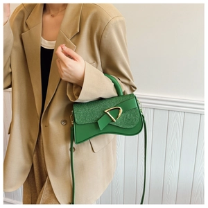 Détail du sac bandoulière vert avec rabat pailleté et boucle dorée en D sur modèle