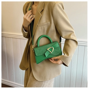 Détail du sac sablier vert montrant texture mate, tissu pailleté et anneau en D doré