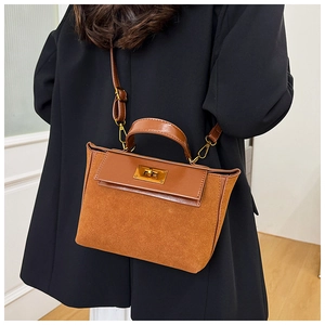 Detail of brown vintage crossbody bag with gold twist lock and black blazer contrast