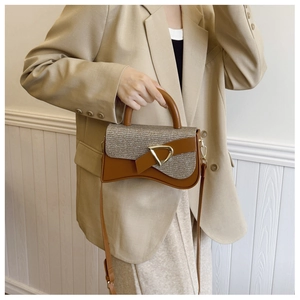 Détail d'un sac selle en cuir marron avec boucle en D dorée et sequins brillants