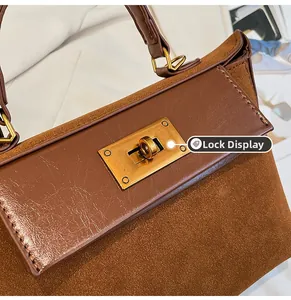Detail of the golden twist-lock closure on a brown vintage leather and suede handbag