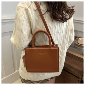 Brown leather crossbody bag with FASHION BAG embossing shown on a model