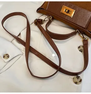 Detail of brown leather tote featuring gold metal twist lock and detachable shoulder strap