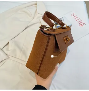 Detail view of the vintage brown handbag showing premium suede side panels and gold clasp