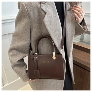 Dark brown matte PU leather tote bag with gold lettering shown on model in modern interior