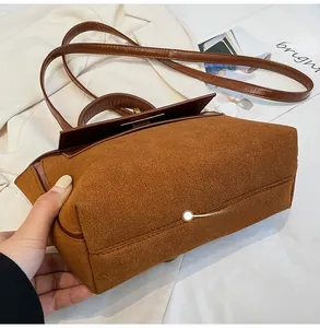 Detailed bottom view showing caramel suede texture and leather stitching of the handbag