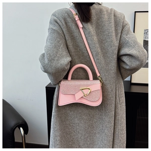 Détail du sac boîte rose avec boucle triangle dorée sur un manteau en laine gris