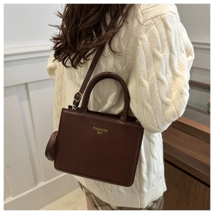 Detail of dark brown leather handbag with gold fashion bag lettering and matching coin purse