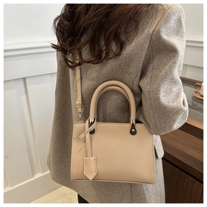 Chic beige crossbody square bag worn with a gray wool blazer in a modern interior setting