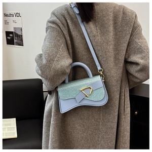 Détail du rabat pailleté et de la base incurvée d'un sac bandoulière bleu menthe