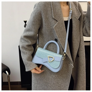 Détail du sac boîte bleu clair avec rabat pailleté, boucle D dorée et bandoulière amovible