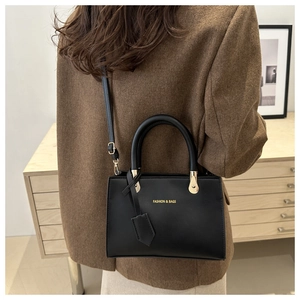Detail of minimalist black matte leather crossbody bag with golden hardware and fashion logo