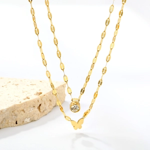 Detailed view of layered gold butterfly necklace with round zircon pendant on white stone