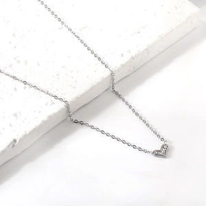 Detail of a silver heart pendant necklace with shimmering pavé set crystals on a stone base