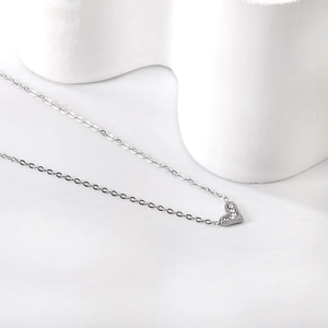Detailed view of silver heart pendant with sparkling white zircons on minimalist chain
