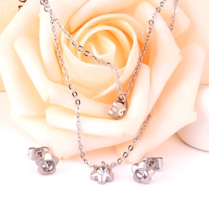 Silver flower jewelry set with sparkling crystal pendants shown on a rose petal