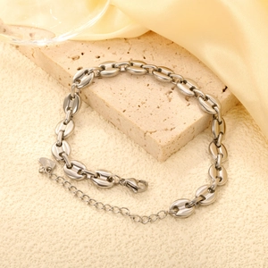 Silver stainless steel coffee bean link bracelet with heart tag on a cream stone base
