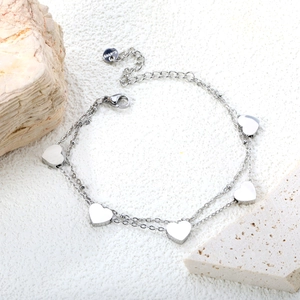 Macro detail of silver double-layered heart charm bracelet in polished stainless steel