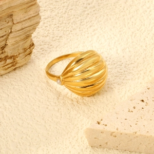 Dettaglio macro di anello a conchiglia dorato con piccola perla su sfondo di pietra