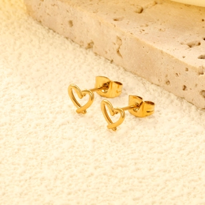 Créoles dorées minimalistes en forme de cœur avec fermoirs papillon sur socle en pierre