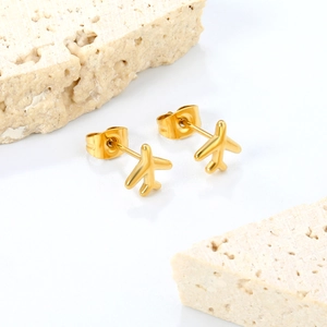 Gros plan de boucles d'oreilles avion en acier inoxydable doré 18K sur pierre