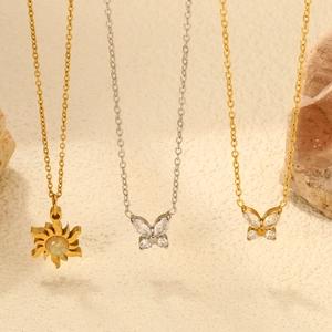 Elegant stainless steel butterfly and sun pendants on textured natural stone background