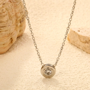 Silver stainless steel necklace with round solitaire pendant on a beach-themed background