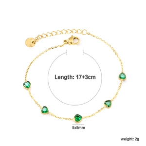 Détail d'un bracelet doré avec zircons émeraude en cœur et fermoir mousqueton réglable