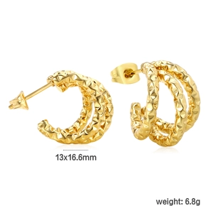 Macro shot of gold-plated geometric C-shape earrings showing diamond-cut texture and size