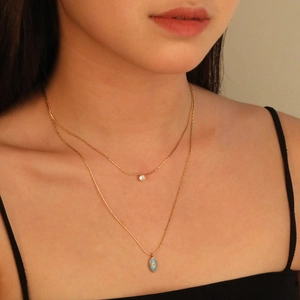 Double-layered gold stainless steel necklace with blue evil eye and sparkling crystal pendant