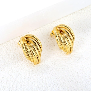 Elegant gold twisted rope earrings with textured metal finish on a marble surface