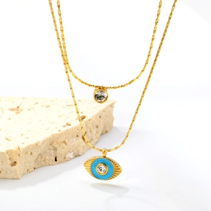 Detail of gold double layer necklace with evil eye pendant and zircon on white stone