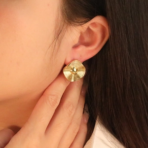 Close-up of vintage golden square earrings with concentric wave pattern on a model