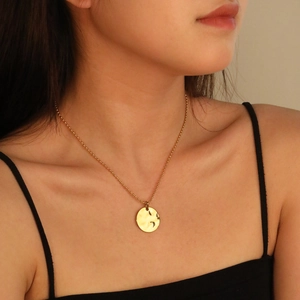 Close-up of a gold geometric textured pendant necklace worn on a model's neck