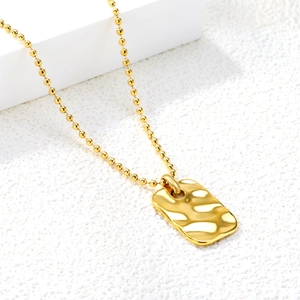 Detail of 18K gold plated rectangular pendant with irregular hammered wave texture
