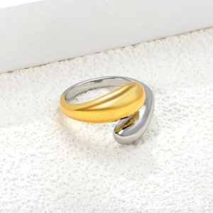 Minimalist bicolor snake-shaped ring in 18k gold and silver tones on stone background