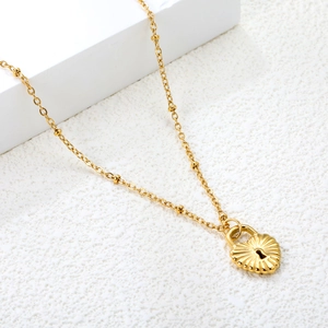 Collier à pendentif cadenas cœur doré 18K sur support géométrique blanc élégant