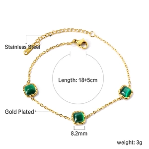 Détail d'un bracelet tennis en acier doré avec des pierres carrées vert émeraude