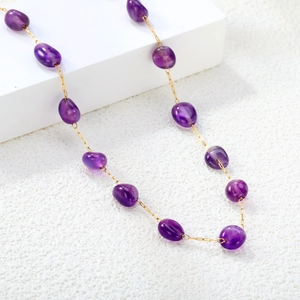 Elegant gold necklace featuring natural translucent purple amethyst stones on a white background