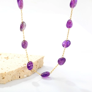 Macro shot of irregular purple amethyst beads and gold stainless steel chain detail